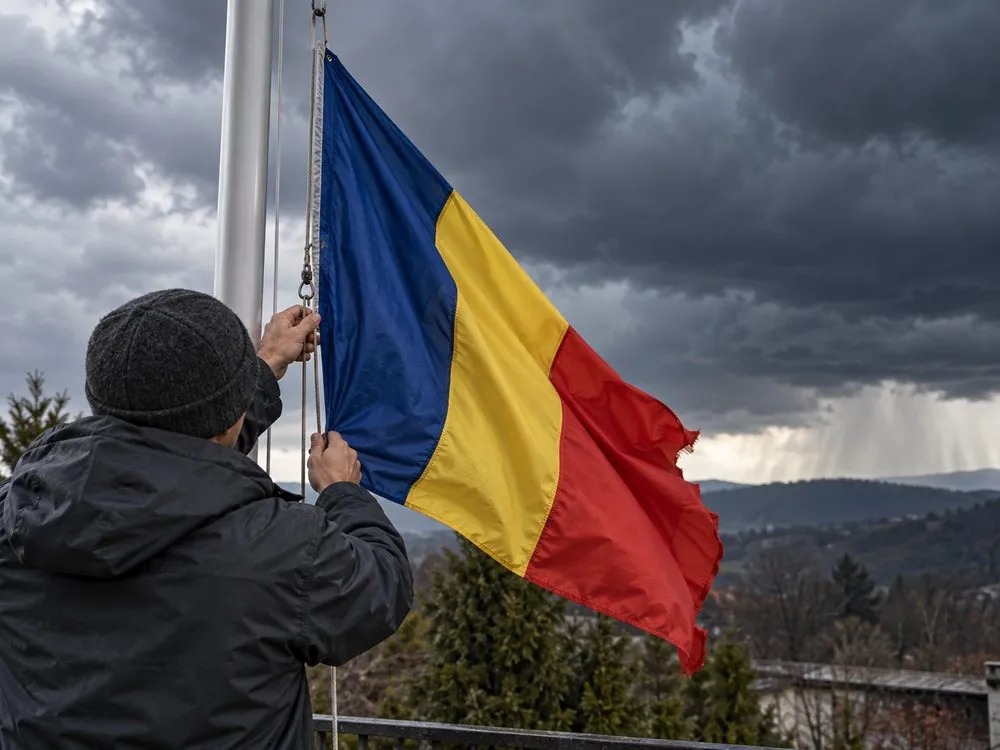 Lowering a flag of Romania from a flagpole before a storm